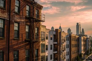 unset over historic brick rowhomes and modern apartment buildings in Philadelphia, with Center City skyscrapers in the background